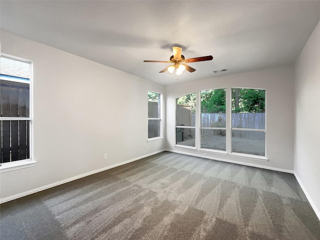 spare room with ceiling fan, carpet floors, visible vents, and baseboards