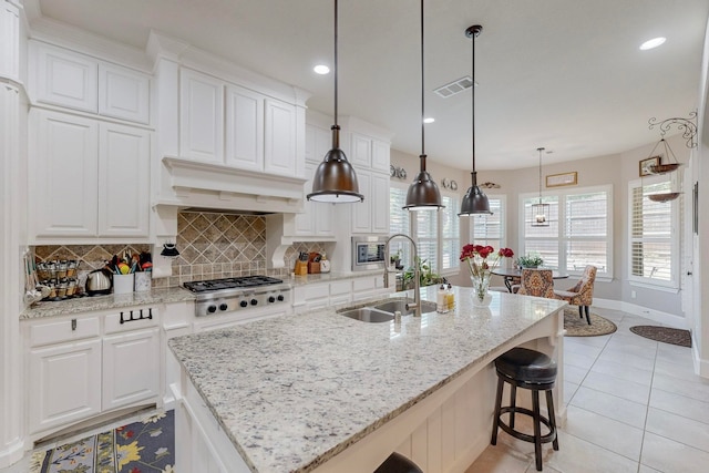 kitchen with pendant lighting, appliances with stainless steel finishes, sink, decorative backsplash, and white cabinetry