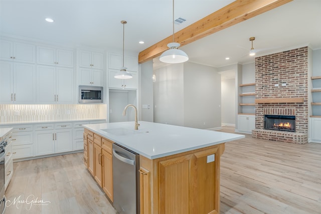 kitchen featuring a center island with sink, white cabinets, sink, beamed ceiling, and stainless steel appliances