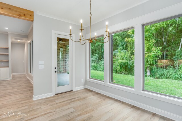 unfurnished dining area with light wood-type flooring, crown molding, baseboards, and an inviting chandelier