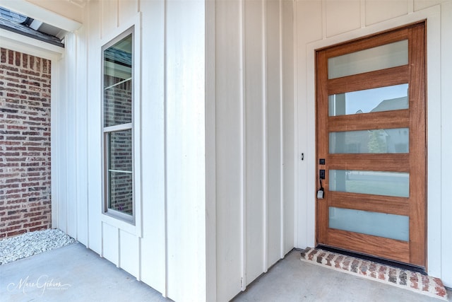 view of exterior entry featuring brick siding and board and batten siding