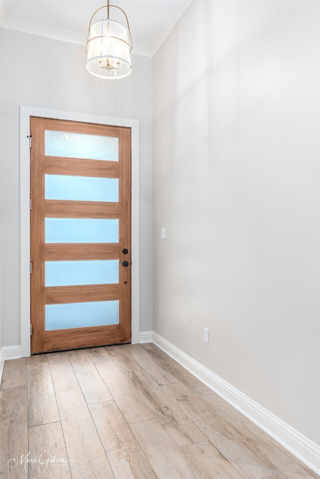 entrance foyer featuring ornamental molding, baseboards, a notable chandelier, and light wood finished floors