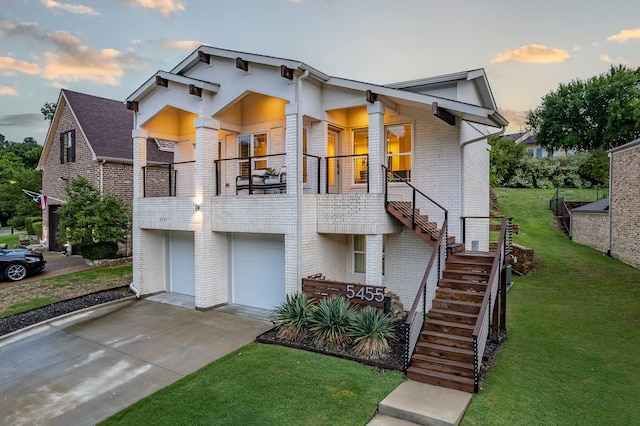 view of front of house with a balcony, a garage, and a yard