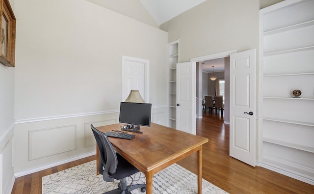 home office with lofted ceiling, wood-type flooring, and built in features