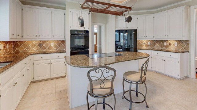 kitchen with white cabinets, a center island, black appliances, tasteful backsplash, and a breakfast bar