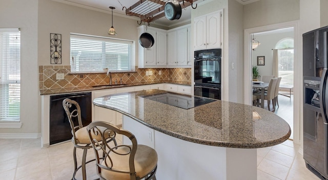 kitchen with black appliances, white cabinets, sink, a wealth of natural light, and dark stone counters