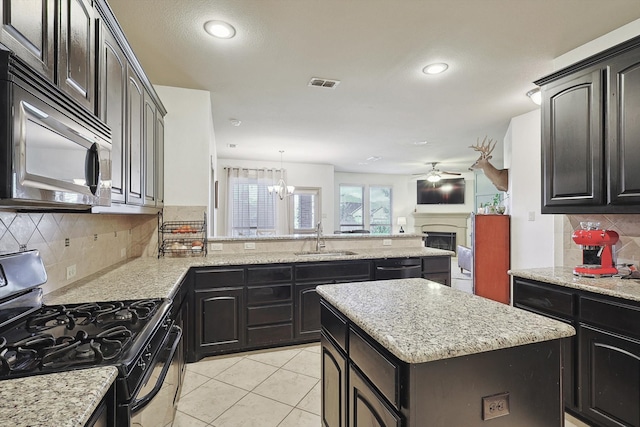 kitchen with appliances with stainless steel finishes, sink, a center island, hanging light fixtures, and decorative backsplash