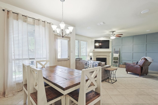 tiled dining room featuring ceiling fan with notable chandelier