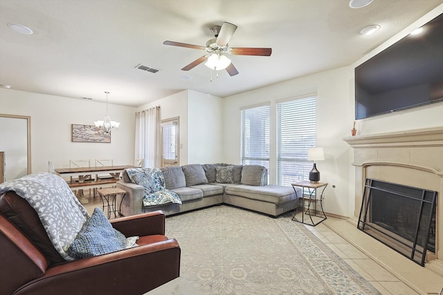 tiled living room with ceiling fan with notable chandelier