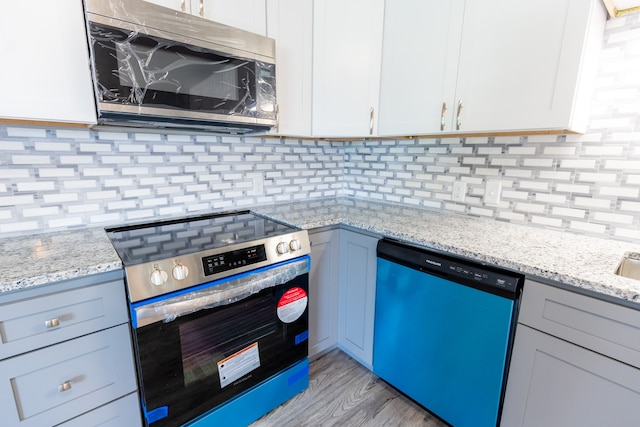 kitchen with appliances with stainless steel finishes, tasteful backsplash, light hardwood / wood-style flooring, and white cabinets