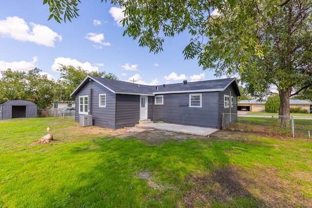 back of property with central AC unit, a yard, and a shed