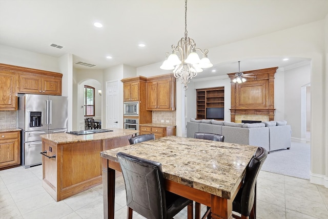 kitchen featuring a center island, stainless steel appliances, ceiling fan with notable chandelier, and tasteful backsplash