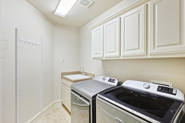 washroom with cabinets, washing machine and dryer, light tile patterned floors, and sink