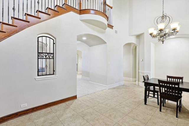 dining area featuring a towering ceiling, light tile patterned floors, and a notable chandelier