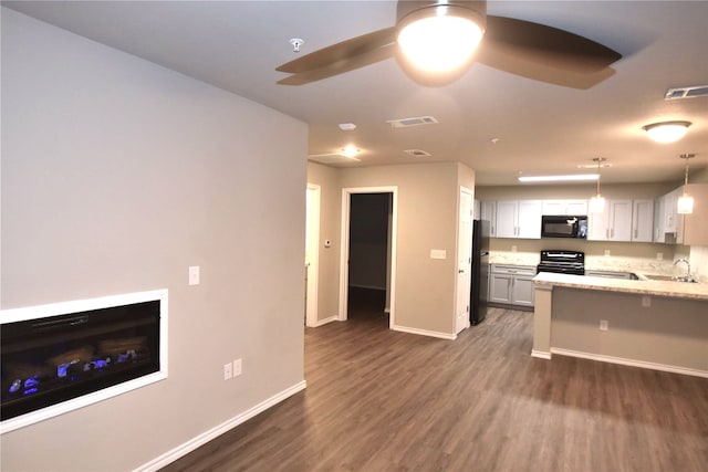 kitchen with dark wood-type flooring, light stone countertops, pendant lighting, black appliances, and ceiling fan