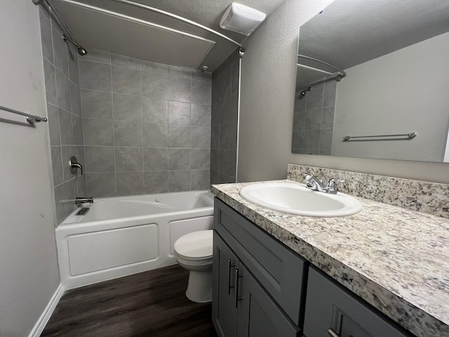 full bathroom featuring a textured ceiling, vanity, hardwood / wood-style floors, toilet, and tiled shower / bath