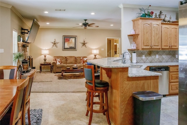 kitchen with tasteful backsplash, light brown cabinetry, light stone countertops, ceiling fan, and stainless steel dishwasher