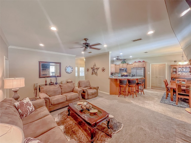 living room with ceiling fan, ornamental molding, and light carpet