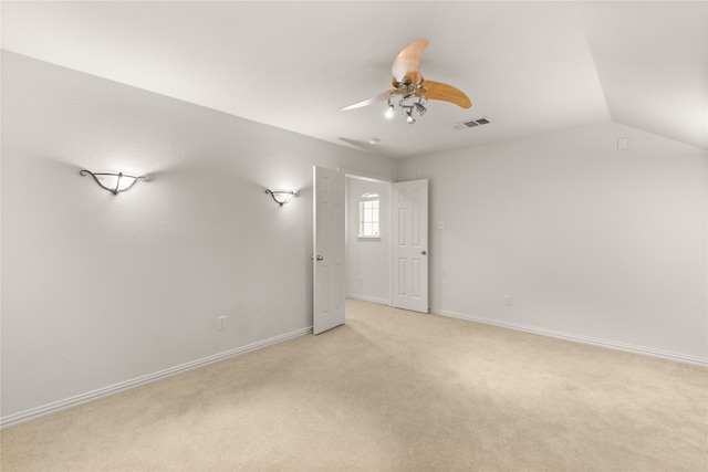 empty room featuring lofted ceiling, ceiling fan, and light carpet