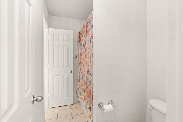 bathroom featuring a shower with shower curtain, toilet, and tile patterned floors