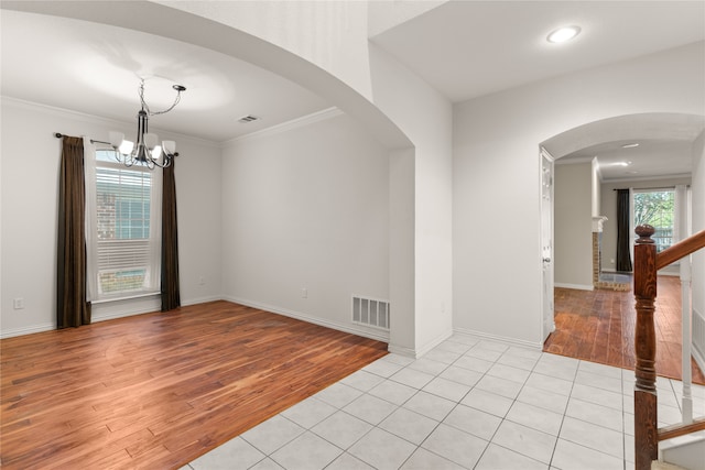 tiled spare room with ornamental molding and an inviting chandelier