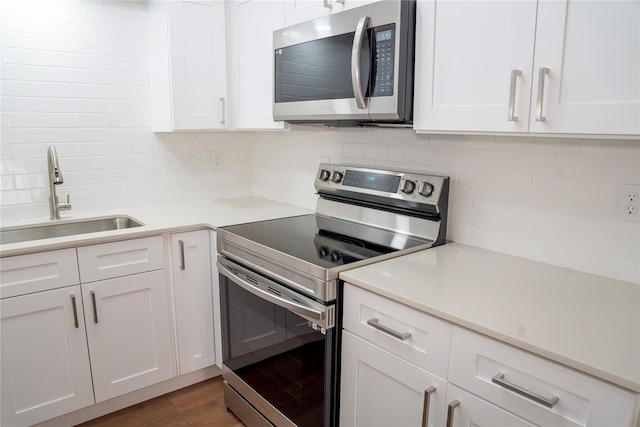 kitchen featuring appliances with stainless steel finishes, decorative backsplash, dark hardwood / wood-style flooring, and sink