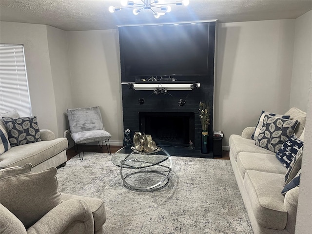 living room featuring a fireplace, a chandelier, and a textured ceiling