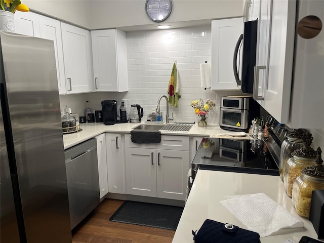 kitchen featuring white cabinets, backsplash, stainless steel appliances, sink, and dark wood-type flooring