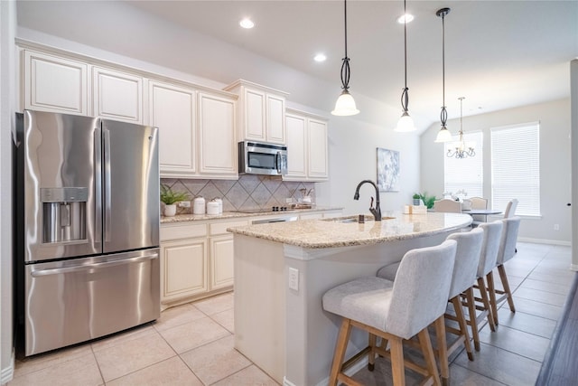 kitchen featuring a sink, appliances with stainless steel finishes, decorative backsplash, light stone countertops, and a kitchen bar