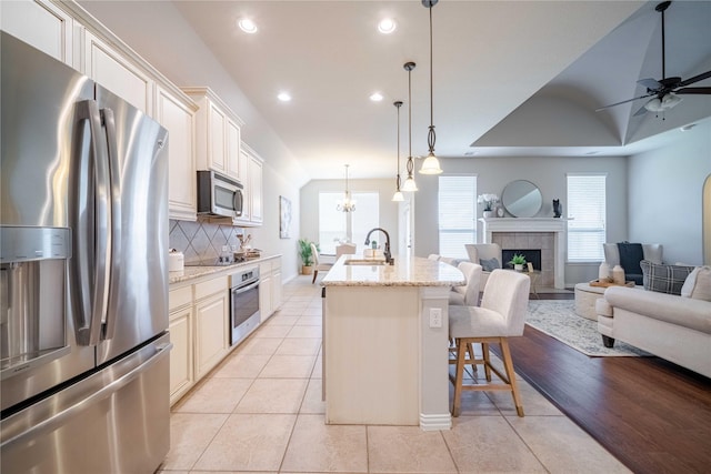 kitchen featuring appliances with stainless steel finishes, open floor plan, a fireplace, and a sink