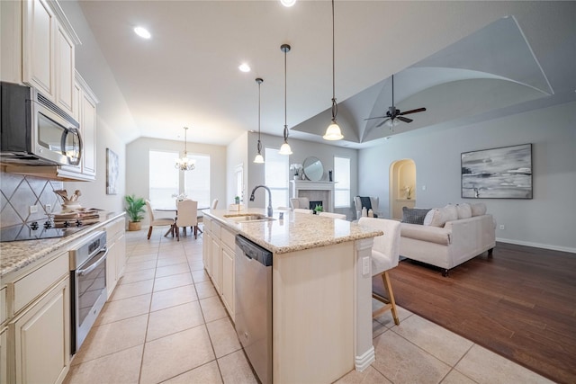 kitchen with a breakfast bar, lofted ceiling, appliances with stainless steel finishes, light tile patterned flooring, and a sink