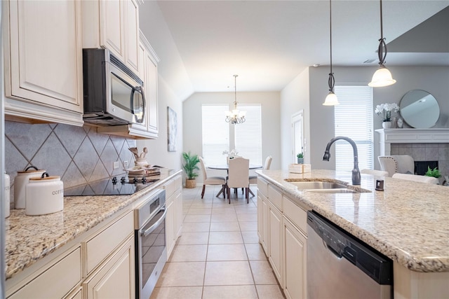 kitchen with light tile patterned floors, backsplash, a tiled fireplace, appliances with stainless steel finishes, and a sink