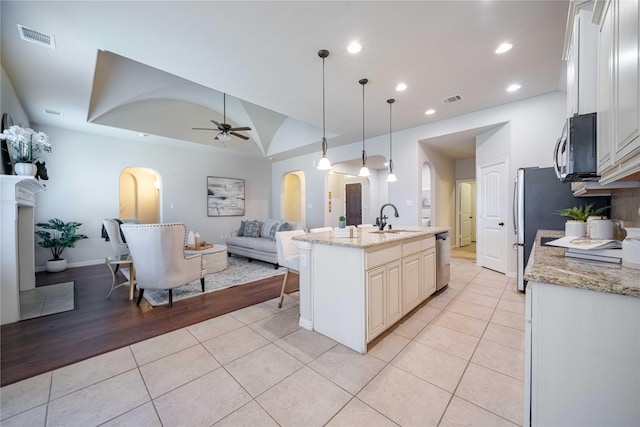 kitchen with light tile patterned floors, arched walkways, a sink, and visible vents