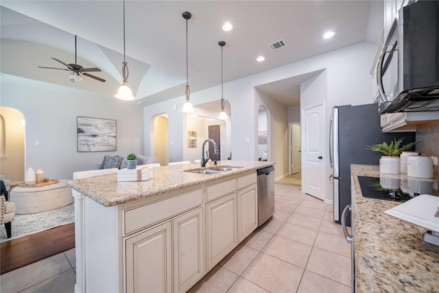 kitchen featuring arched walkways, dishwasher, open floor plan, vaulted ceiling, and a sink