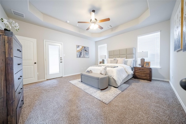 bedroom featuring carpet floors, visible vents, a tray ceiling, and baseboards