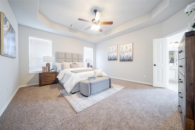 bedroom with baseboards, visible vents, a tray ceiling, and carpet flooring