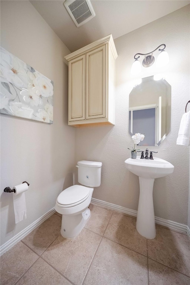 half bathroom with baseboards, visible vents, toilet, and tile patterned floors