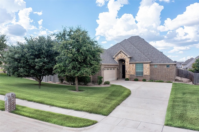 view of front of house with a front yard, fence, a garage, stone siding, and driveway