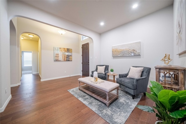 sitting room featuring arched walkways, recessed lighting, baseboards, and wood finished floors