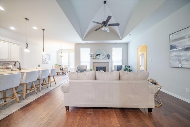 living area with dark wood finished floors, recessed lighting, a tiled fireplace, vaulted ceiling, and baseboards