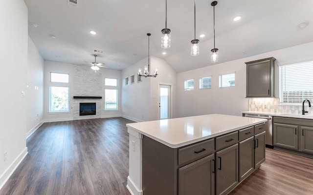 kitchen with stainless steel dishwasher, ceiling fan with notable chandelier, decorative light fixtures, a fireplace, and a center island