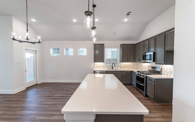 kitchen with appliances with stainless steel finishes, a center island, decorative light fixtures, and vaulted ceiling