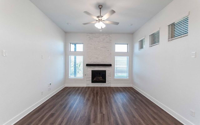 unfurnished living room with ceiling fan, dark hardwood / wood-style flooring, and a stone fireplace