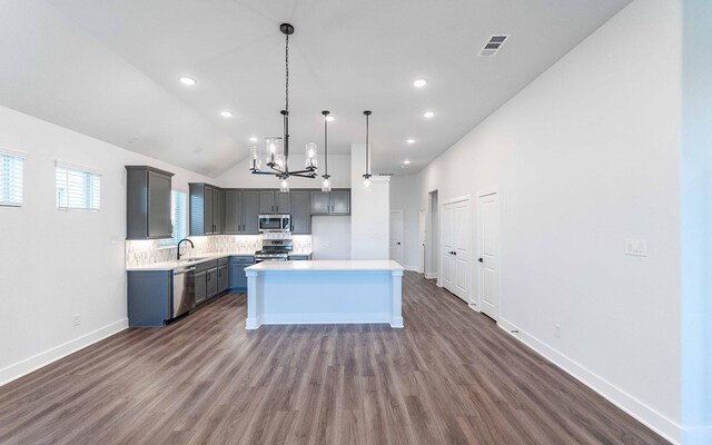 kitchen featuring pendant lighting, a center island, lofted ceiling, sink, and appliances with stainless steel finishes