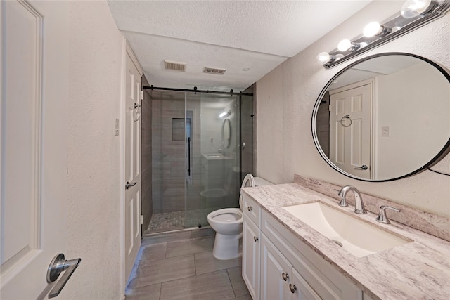 bathroom featuring toilet, tile patterned flooring, a shower with door, vanity, and a textured ceiling