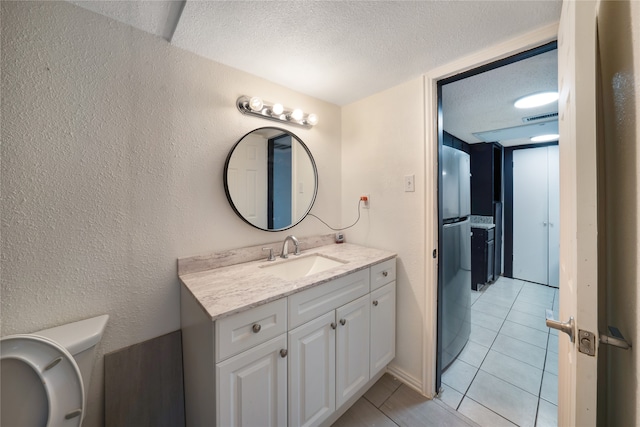 bathroom featuring tile patterned flooring, vanity, toilet, and a textured ceiling