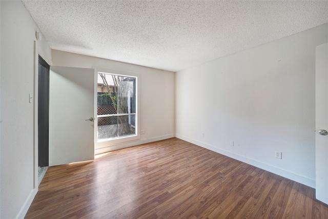 spare room featuring dark wood-type flooring and a textured ceiling