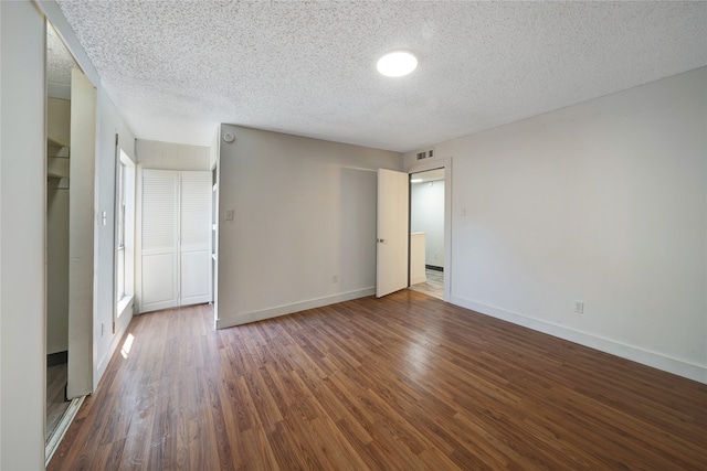 empty room with a textured ceiling and dark hardwood / wood-style flooring