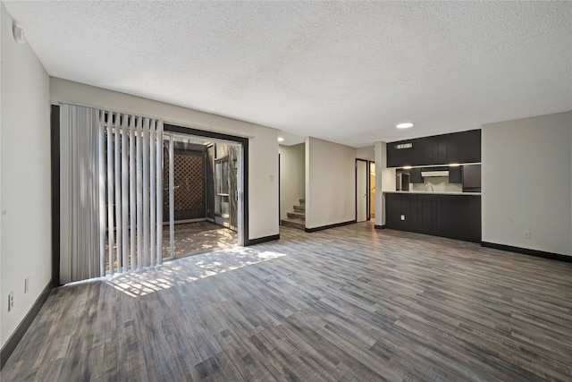 unfurnished living room featuring dark wood-type flooring and a textured ceiling