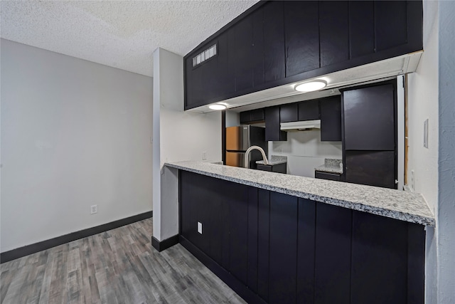 kitchen with stainless steel fridge, a textured ceiling, and hardwood / wood-style floors